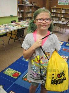 Second grade girl holding back pack full of books